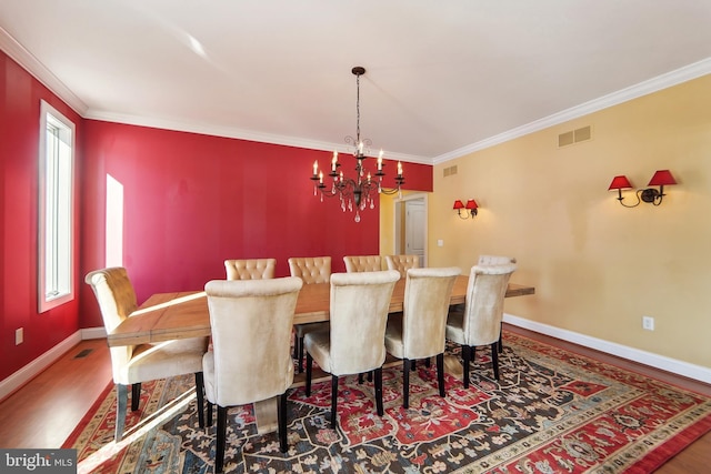 dining space with hardwood / wood-style flooring, an inviting chandelier, and crown molding