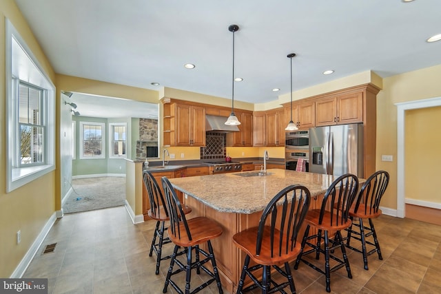 kitchen with sink, hanging light fixtures, a kitchen breakfast bar, extractor fan, and appliances with stainless steel finishes