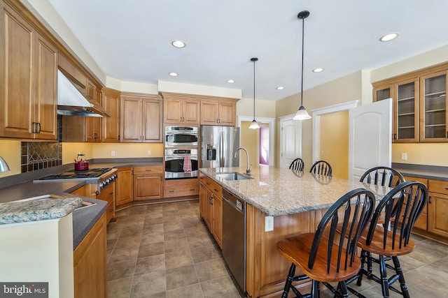 kitchen featuring decorative light fixtures, stainless steel appliances, a breakfast bar, and dark stone counters