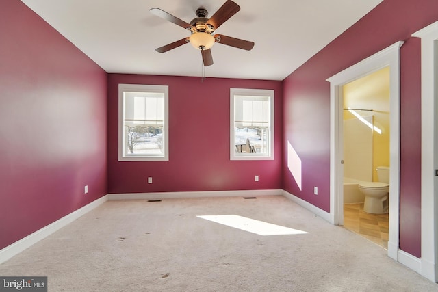 unfurnished bedroom featuring ensuite bath, ceiling fan, and light carpet