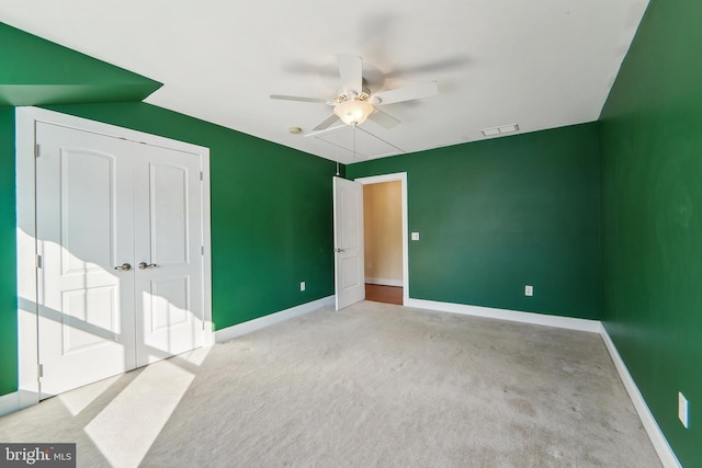 unfurnished bedroom featuring ceiling fan, a closet, and light colored carpet