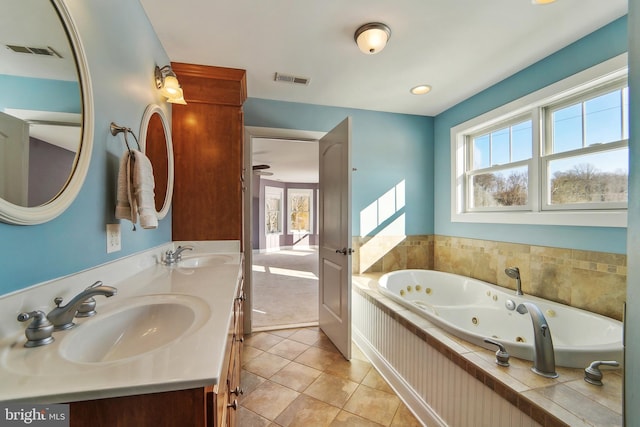 bathroom featuring tile patterned flooring, vanity, and a relaxing tiled tub