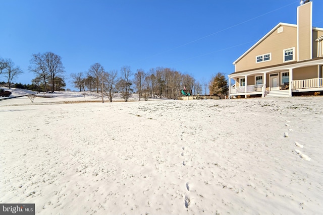 snowy yard featuring covered porch