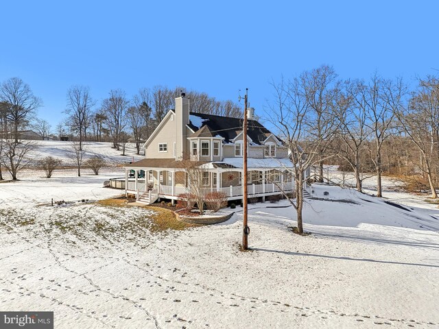 snow covered property with covered porch