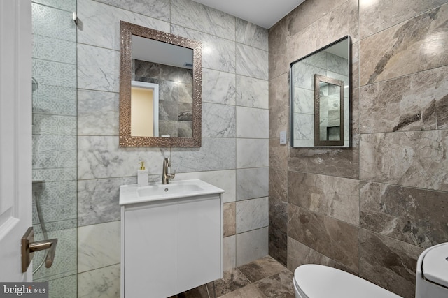 bathroom with vanity, toilet, and tile walls