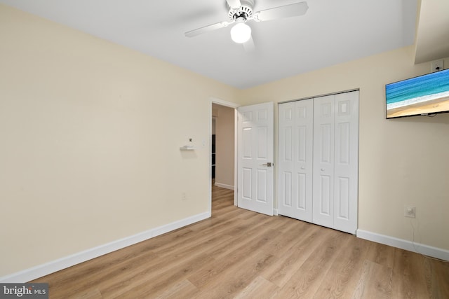 unfurnished bedroom with ceiling fan, light wood-type flooring, and a closet