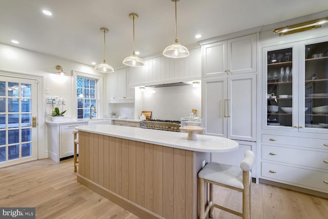 kitchen with light wood-type flooring, a center island, a kitchen bar, white cabinetry, and decorative light fixtures