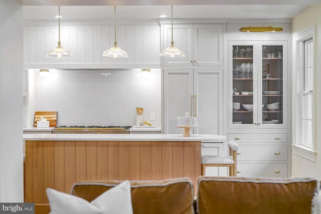 bar featuring stainless steel gas stovetop, pendant lighting, and white cabinetry