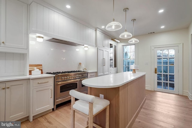 kitchen with a kitchen island, double oven range, and white cabinetry