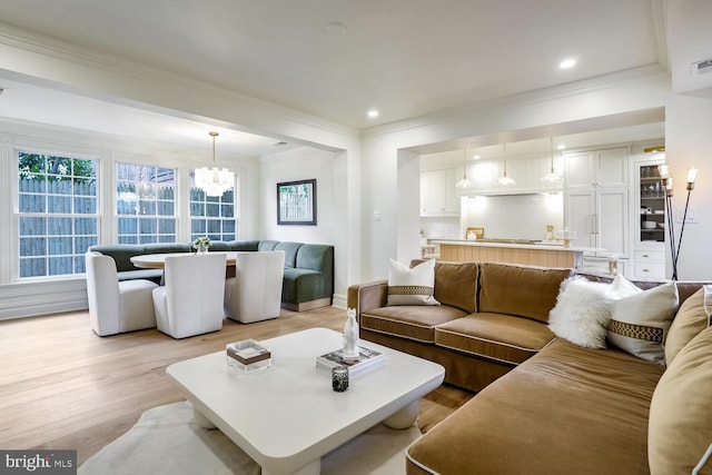 living room featuring crown molding, a notable chandelier, and light hardwood / wood-style flooring