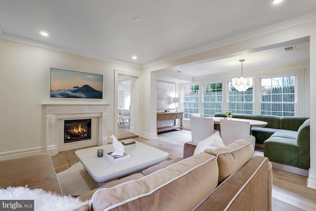 living room featuring crown molding, a notable chandelier, and light hardwood / wood-style flooring