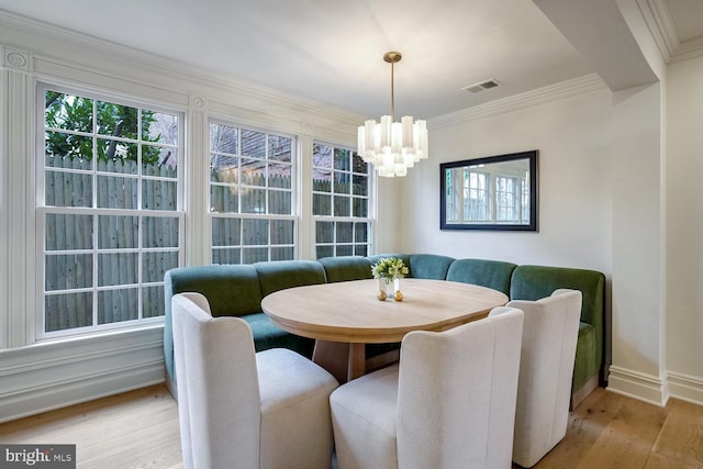 dining room with light hardwood / wood-style floors, crown molding, a chandelier, and breakfast area