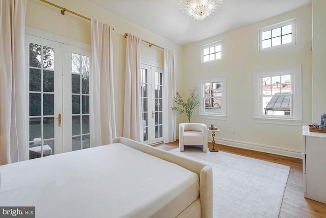 bedroom with a notable chandelier, french doors, and wood-type flooring