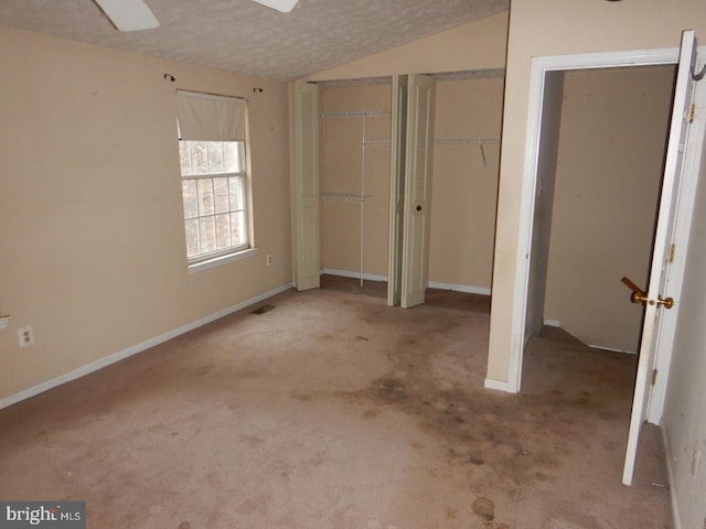 unfurnished bedroom featuring ceiling fan, light colored carpet, a textured ceiling, and vaulted ceiling