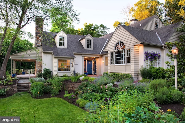 view of front facade with a shingled roof, a chimney, a front lawn, and stucco siding