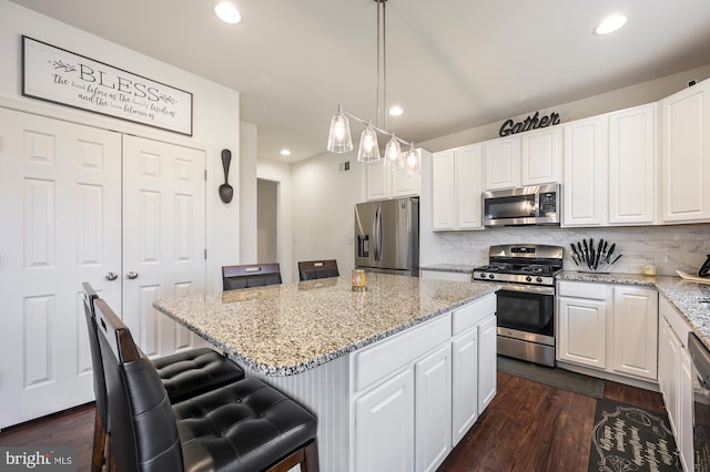 kitchen featuring white cabinetry, a center island, pendant lighting, a breakfast bar, and appliances with stainless steel finishes