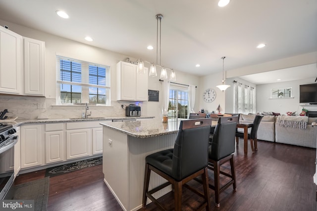 kitchen featuring white cabinetry, stove, a kitchen island, and hanging light fixtures