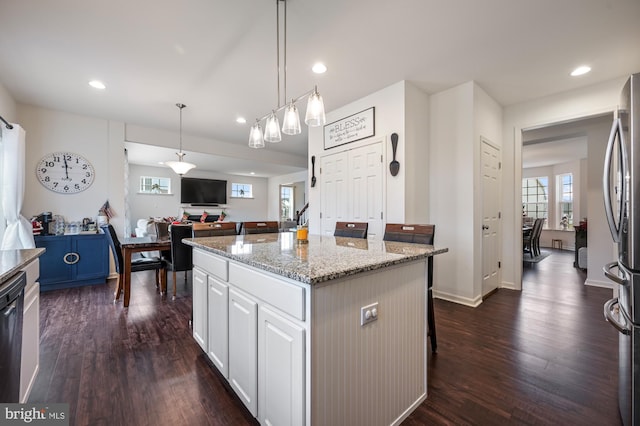 kitchen featuring stainless steel fridge, dark wood-type flooring, a center island, white cabinetry, and hanging light fixtures