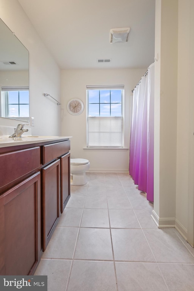 bathroom with tile patterned flooring, a healthy amount of sunlight, and toilet