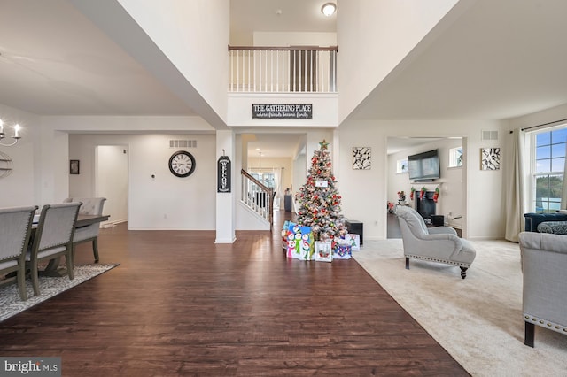 entryway with a towering ceiling, dark wood-type flooring, and an inviting chandelier