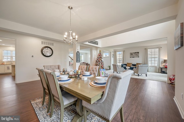 dining room with dark wood-type flooring and a notable chandelier