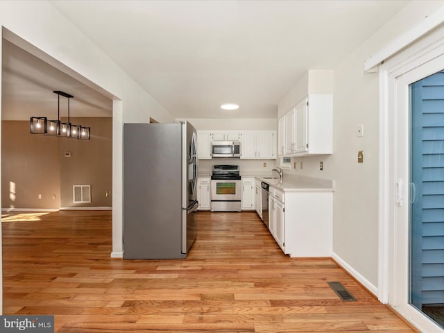 kitchen featuring white cabinetry, sink, pendant lighting, light hardwood / wood-style floors, and appliances with stainless steel finishes