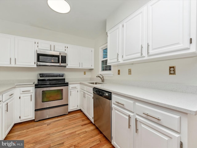 kitchen featuring white cabinets, stainless steel appliances, light hardwood / wood-style floors, and sink