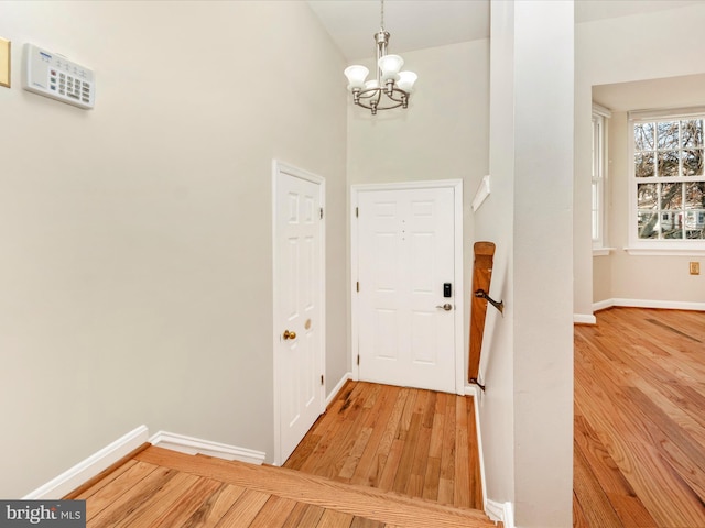 entryway featuring hardwood / wood-style floors, a towering ceiling, and a notable chandelier