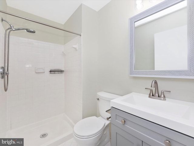 bathroom with tiled shower, vanity, and toilet