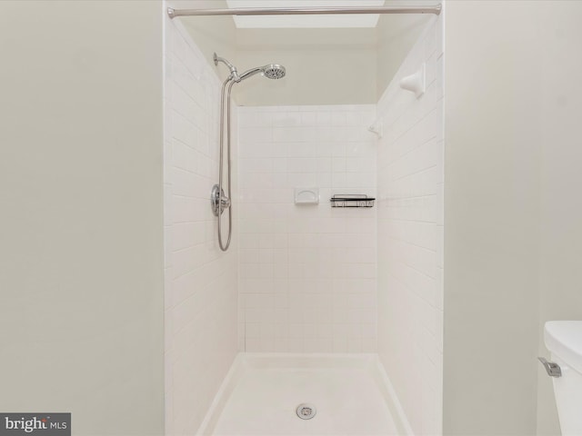 bathroom featuring a tile shower and toilet