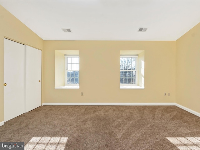 unfurnished bedroom with carpet floors, a closet, multiple windows, and lofted ceiling