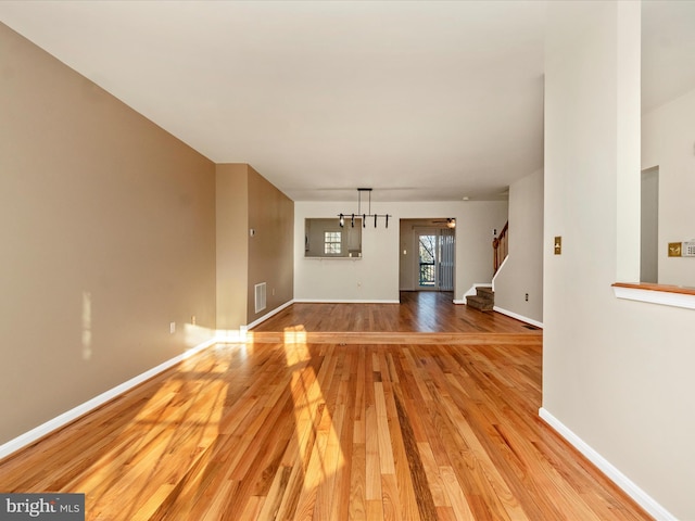 unfurnished living room with light hardwood / wood-style floors and an inviting chandelier