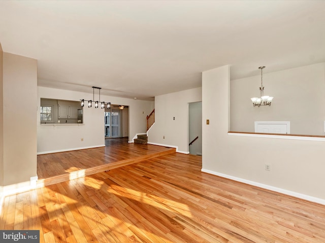 unfurnished living room with a chandelier and light hardwood / wood-style flooring