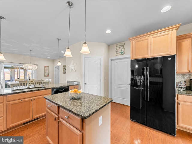 kitchen with backsplash, sink, black appliances, pendant lighting, and a center island