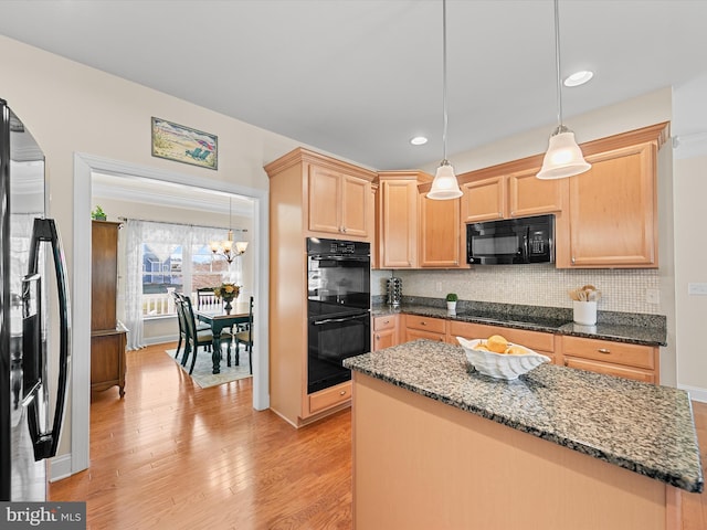 kitchen featuring dark stone counters, black appliances, decorative backsplash, light brown cabinetry, and decorative light fixtures