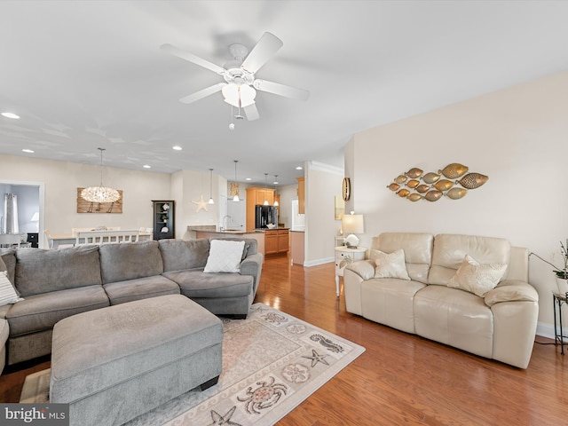 living room with light hardwood / wood-style floors, ceiling fan, and sink