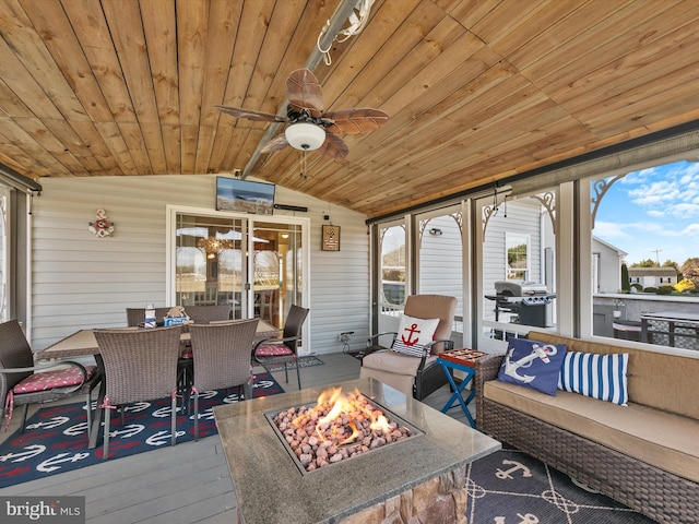 sunroom featuring lofted ceiling, ceiling fan, and wooden ceiling