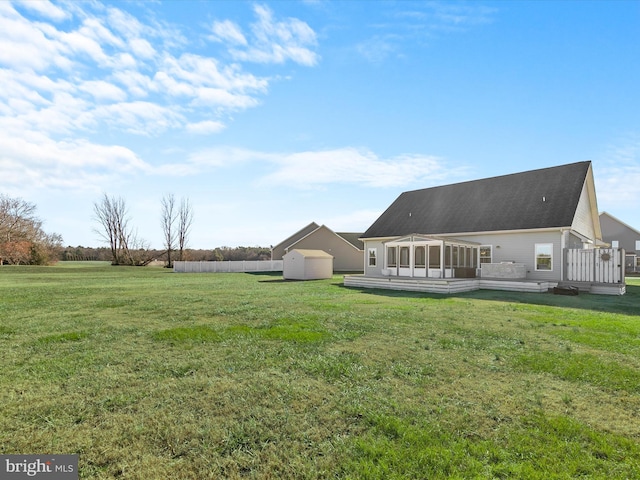 back of property with a sunroom, a deck, and a yard