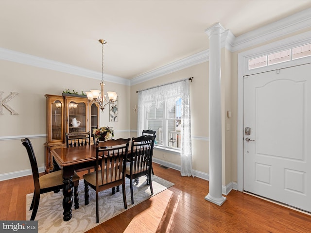 dining room with an inviting chandelier, crown molding, light hardwood / wood-style flooring, and decorative columns