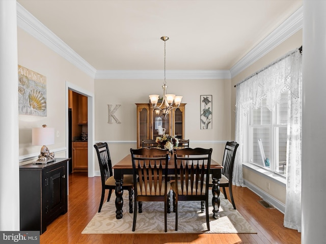 dining room with wood-type flooring, an inviting chandelier, and crown molding