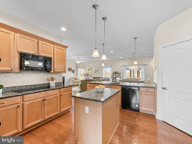 kitchen featuring kitchen peninsula, ceiling fan, black appliances, decorative light fixtures, and a kitchen island