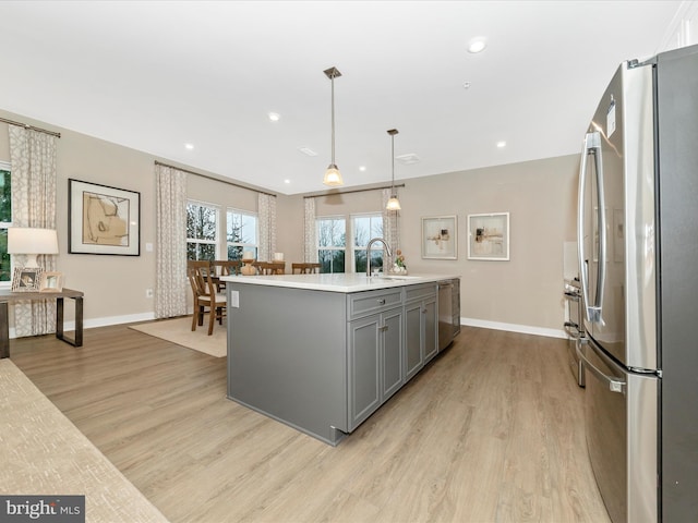 kitchen with pendant lighting, gray cabinetry, appliances with stainless steel finishes, and light hardwood / wood-style flooring