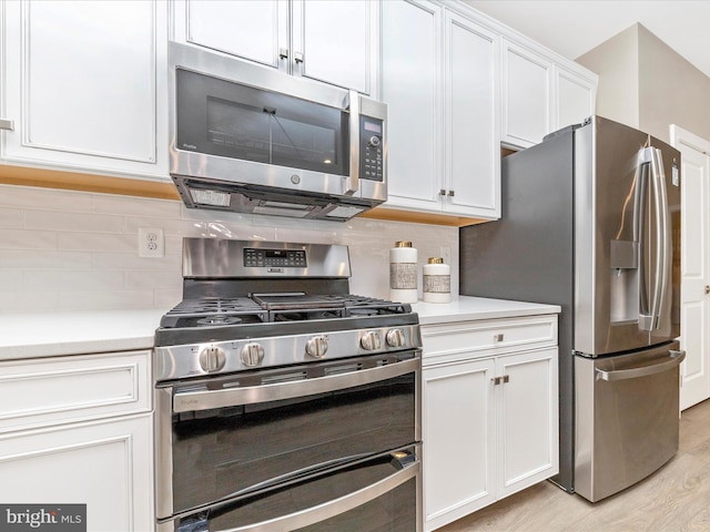 kitchen featuring decorative backsplash, white cabinetry, stainless steel appliances, and light wood-type flooring