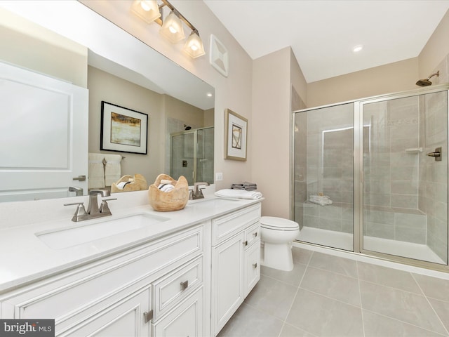 bathroom featuring tile patterned floors, vanity, toilet, and a shower with shower door