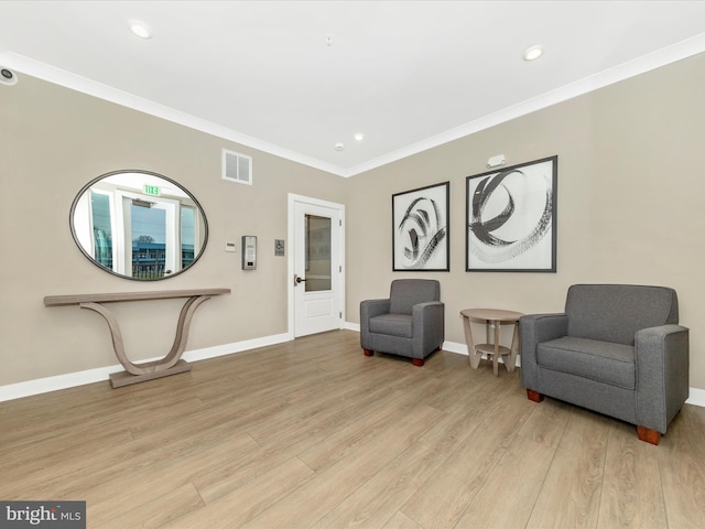 living area with light wood-type flooring and ornamental molding