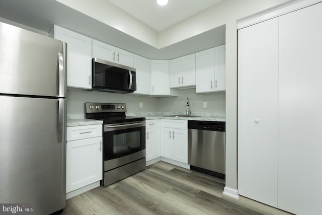 kitchen featuring appliances with stainless steel finishes, light hardwood / wood-style floors, white cabinetry, and sink