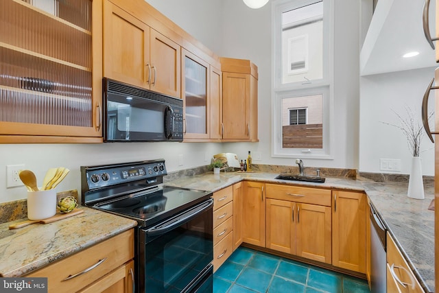 kitchen featuring sink, dark tile patterned flooring, black appliances, and light stone countertops