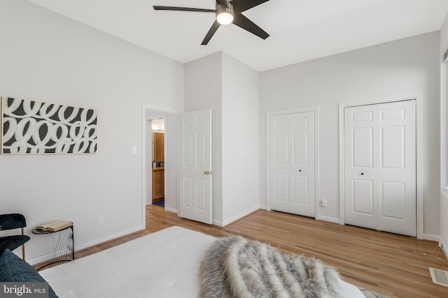 bedroom with two closets, ceiling fan, and light wood-type flooring