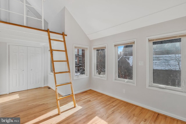 unfurnished bedroom featuring lofted ceiling, a closet, and hardwood / wood-style floors