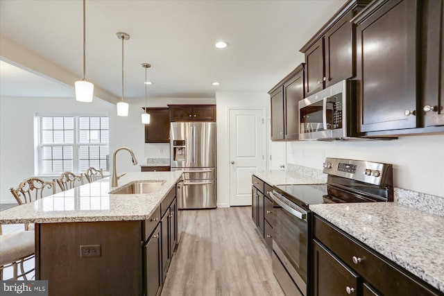 kitchen with stainless steel appliances, sink, pendant lighting, a breakfast bar area, and an island with sink